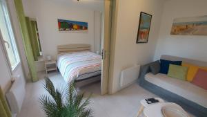 a small room with a bed and a couch at T2, 50m du lac, PISCINE, WIFI, jardin terrasse sans vis-à-vis, 1 à 4 pers in Aureilhan