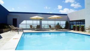 a swimming pool with chairs and umbrellas on a building at hotel tambau flat particular 605 in João Pessoa