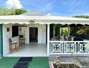une maison blanche avec une véranda et une terrasse dans l'établissement La Maison Créole du Flamboyant - Proche des Plages, à Anse-Bertrand