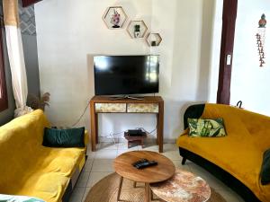 - un salon avec deux canapés jaunes et une télévision dans l'établissement La Maison Créole du Flamboyant - Proche des Plages, à Anse-Bertrand