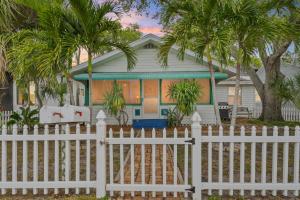 a white fence in front of a house with palm trees at The Pineapple Bungalow St Pete in St Petersburg