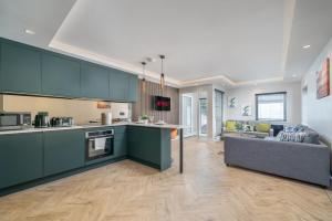 a kitchen with green cabinets and a living room at Skyvillion -COZY & AMAZING King 1Bed Apartment in London Cockfosters Mins to Tube in Cockfosters