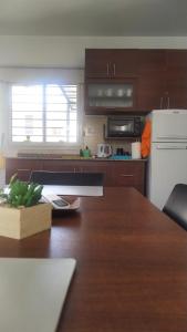 cocina con mesa de madera y nevera blanca en Dpto 1 dormitorio a 2 cuadras de Parque de Mayo, en San Juan 5 fotos más