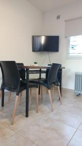 mesa de comedor con sillas negras y TV de pantalla plana en Dpto 1 dormitorio a 2 cuadras de Parque de Mayo, en San Juan