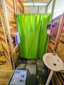 a bathroom with a green shower curtain and a sink at Arboura Eco Cabins in Uvita