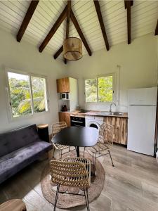 cocina y sala de estar con mesa y sillas en gîte de forêt de Guadeloupe, en Petit-Bourg