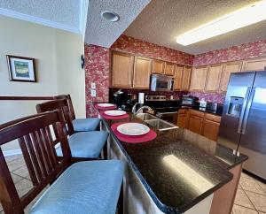 eine Küche mit einer Theke mit Stühlen und einem Kühlschrank in der Unterkunft South Shore 1202 condo in Myrtle Beach