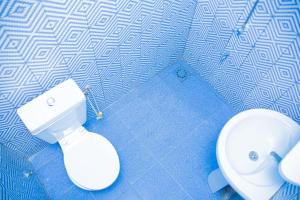 a bathroom with a white toilet and a blue wall at Parakou's Paradise in Parakou