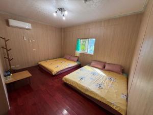 two beds in a small room with wooden floors at Mido Hao B&B in Luye +3 photos