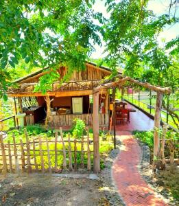 ein Holzhaus mit einem Zaun und einer Terrasse in der Unterkunft TINA LAKESIDE AO ĐÔI Homestay Phước Hải in Hội Mỹ