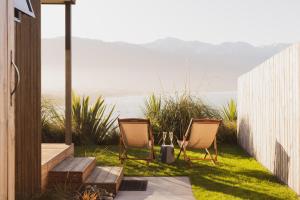 two chairs sitting on a lawn with a view of the ocean at Clifftop Cabins in Kaikoura +14 photos