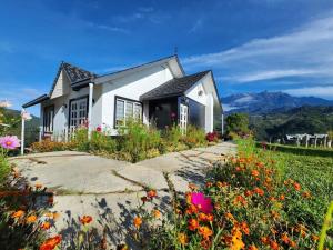 ein Haus mit einem Blumengarten davor in der Unterkunft Spectacular Mt Kinabalu view 2 Bedroom cottage in Ranau