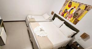 a small room with two beds and a painting on the wall at Pousada João Sol in Praia do Forte