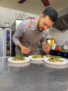 Un uomo in una cucina con tre piatti di cibo di Casa Bonita a Guadalajara