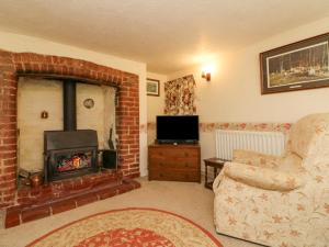 a living room with a fireplace and a chair and a television at The Cottage in Bideford