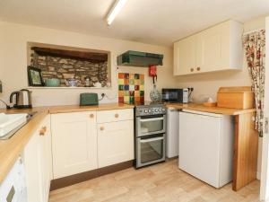 a kitchen with white cabinets and a stove top oven at The Cottage in Bideford