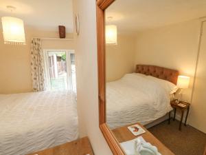 ein Schlafzimmer mit einem Spiegel, einem Bett und einem Tisch in der Unterkunft The Cottage in Bideford