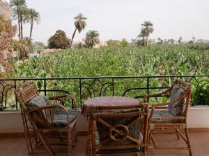 a table and chairs on a balcony with a field of corn at Villa Quiet Place in Luxor