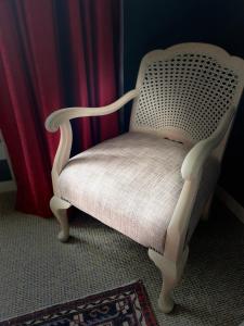 einen weißen Stuhl in einem Zimmer mit einem roten Vorhang in der Unterkunft Bavaria Boutique Hotel in Auckland