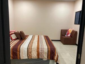 a bedroom with a bed and a chair at Vacacional Abril in Juayúa