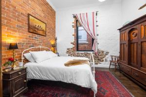 a bedroom with a bed and a brick wall at Arapiles Club House in Natimuk +12 photos