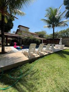 a row of white chairs sitting next to a pool at Casa San Francisco in Porto Seguro