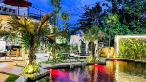 a garden with a pond with palm trees and a building at The Luxury in Siem Reap