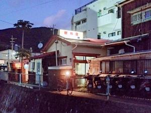 a train on the tracks in front of a building at Amami Guest House showa-so in Setouchi