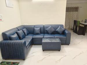 a blue leather couch in a living room at Hasinihomes 3bhk brand new new service apartment JNTU nizampet pragathi nagar in Hyderabad