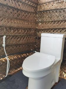a white toilet in a bathroom with a wall at Basecamp - Yala in Yala