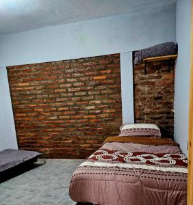 a bed in a room with a brick wall at El gumer in San Fernando del Valle de Catamarca