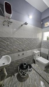 uma casa de banho com um lavatório, um WC e uma televisão em THE STAY CORNER em Guwahati