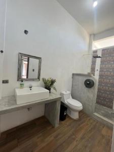 La salle de bains est pourvue d'un lavabo, de toilettes et d'un miroir. dans l'établissement MAYAN SURF HOTEL, à El Paredón Buena Vista