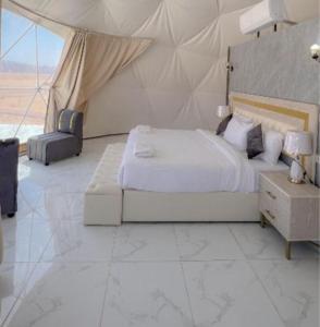 a white bedroom with a bed and a large window at Lukasa camp Wadi Rum in Wadi Rum