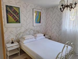 1 dormitorio con cama blanca en una habitación con papel pintado en Apartment Srsen, en Kućište