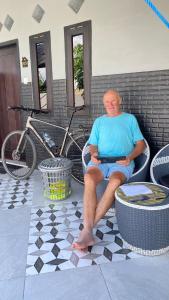 Ein Mann, der auf einer Terrasse auf einem Stuhl sitzt in der Unterkunft Juliana HomeStay 
