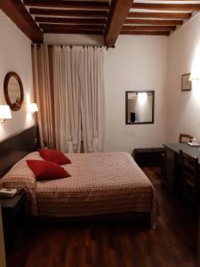 a bedroom with a bed with red pillows on it at Hotel Borgo Antico in Bibbiena