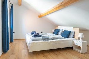 una camera da letto con un letto bianco con cuscini blu di Via Paradiso Apartments a Piran
