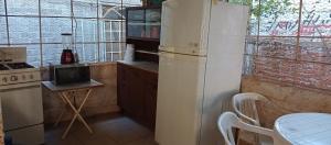 a kitchen with a white refrigerator and a table at Villas Carmelita hostal in Paso de las Palmas