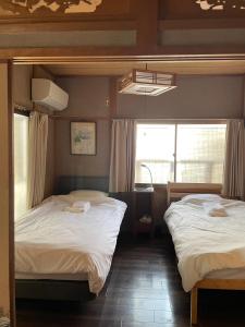 two twin beds in a room with two windows at LAZYHOUSE 別邸 in Okayama
