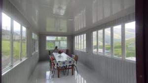 a dining room with a table and chairs and windows at Zaur Guest hause in Xınalıq