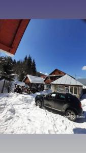 ein im Schnee vor einem Haus geparktes Auto in der Unterkunft Cabana Larisa in Cavnic