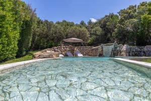 einen Pool in einem Garten mit Bäumen und Felsen in der Unterkunft Villa Pevero Porto Cervo in Porto Cervo