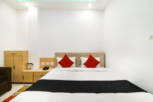 um quarto com uma cama branca e almofadas vermelhas em Capital O 61009 Hotel Raj Mahal Sarnath em Varanasi