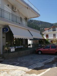 a red car parked in front of a building at Hotel Fotini in Kamena Vourla