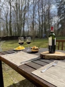 a wooden table with a bottle of wine and two glasses at Gîte Les Reculons au pied du lac in Les Midoux