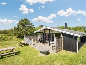 une petite cabine noire avec une table de pique-nique et des bancs dans l'établissement 6 person holiday home in Fan, à Fanø