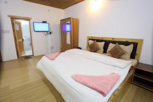 a bedroom with a large bed with a television on the wall at Odbar Guest House Best Guest House at Leh Ladakh in Leh