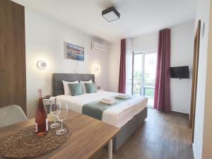 a hotel room with a bed and a table with wine glasses at Bofani Apartments Budva in Budva