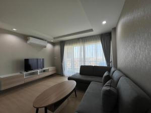 a living room with a couch and a tv at Suntomoon Residence By Sumo Ayutthaya อยุธยา in Phra Nakhon Si Ayutthaya